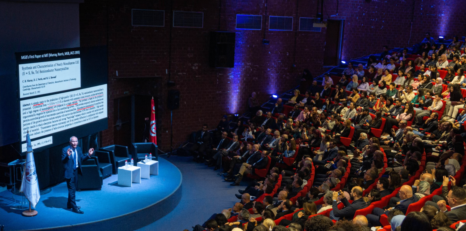 Keynote speaker at auditorium with red seats